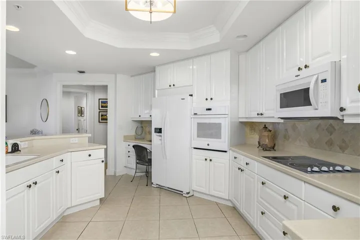 Kitchen with ornamental molding, white cabinets, white appliances, and a tray ceiling