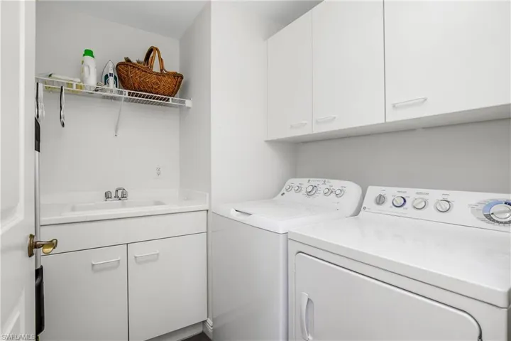 Laundry room with separate washer and dryer, sink, and cabinets