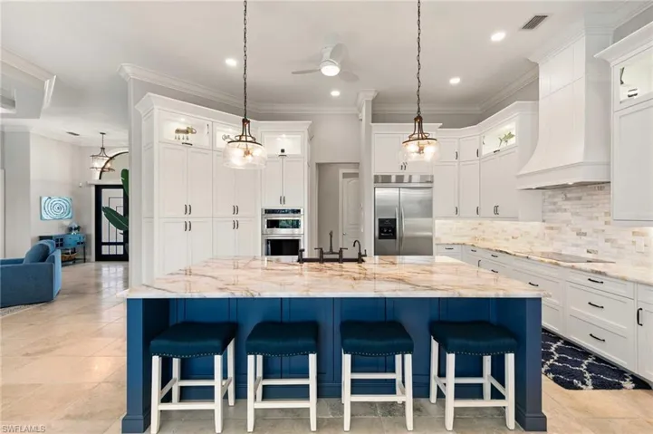 Kitchen featuring glass insert cabinets, ornamental molding, decorative backsplash, a breakfast bar, and appliances with stainless steel finishes
