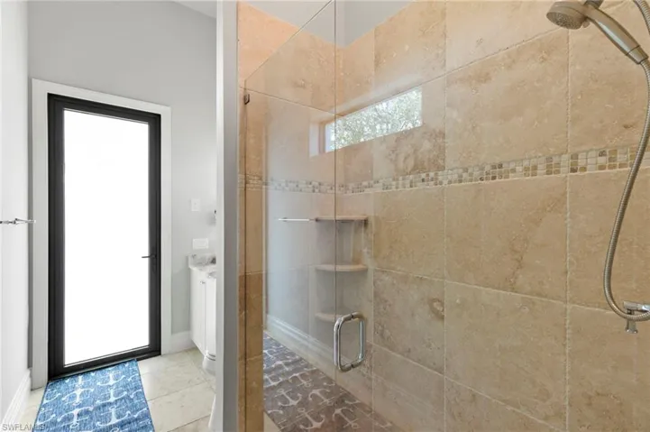 Full bath featuring a shower stall and light tile patterned floors