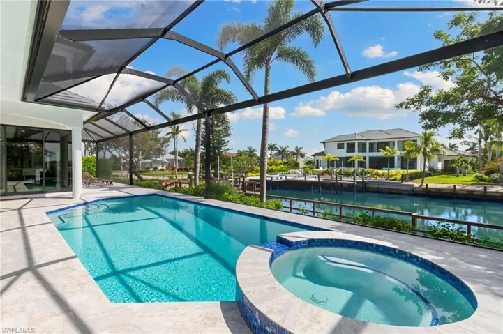 View of swimming pool with a patio area, a sunroom, a water view, a pool with connected hot tub, and a lanai