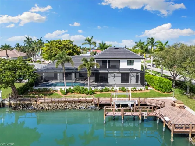 Rear view of house featuring a water view, boat lift, a sunroom, and an outdoor pool