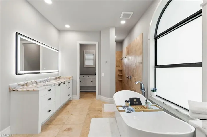 Bathroom featuring vanity, a freestanding tub, tiled shower, recessed lighting, and light tile patterned floors