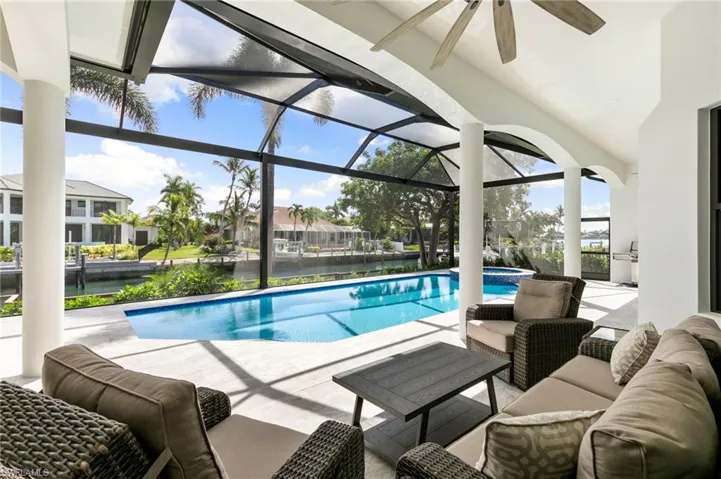 View of pool with a patio, a sunroom, a water view, a pool with connected hot tub, and glass enclosure