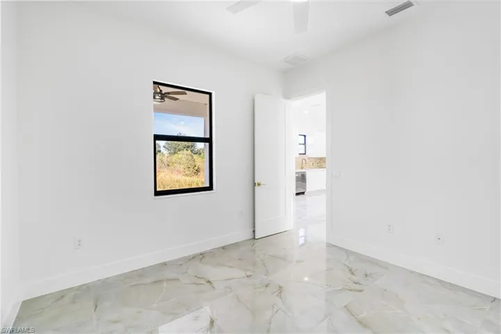 Unfurnished room featuring light marble finish floors and ceiling fan