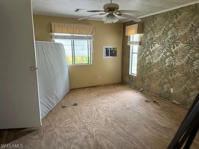 Unfurnished room featuring a textured ceiling, ceiling fan, and crown molding