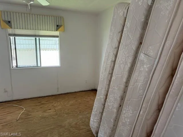 Unfurnished room with hardwood / wood-style floors, ceiling fan, and crown molding