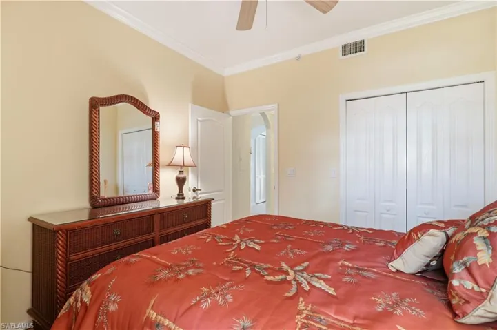Bedroom featuring ornamental molding, a closet, a ceiling fan, and arched walkways