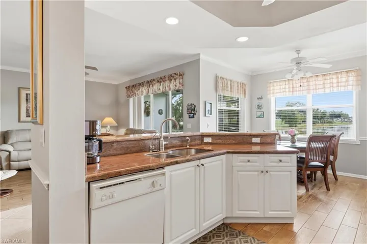Kitchen featuring a ceiling fan, white cabinets, white dishwasher, wood finish floors, and dark stone counters