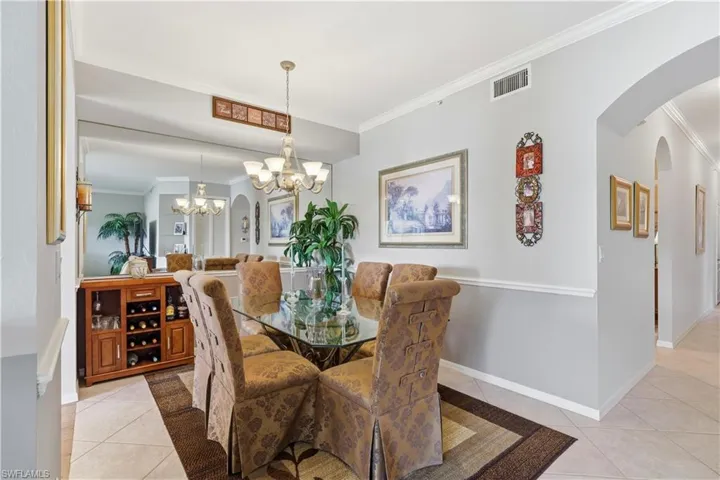 Dining room with arched walkways, crown molding, light tile patterned floors, and a chandelier