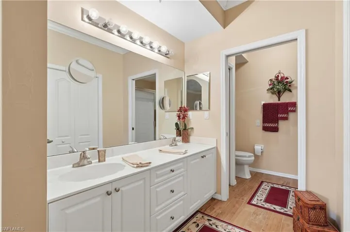 Full bathroom featuring double vanity, light wood finished floors, and crown molding