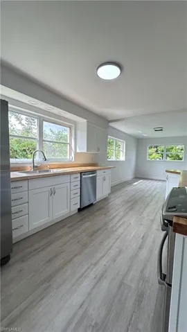 Kitchen featuring sink, light hardwood / wood-style flooring, stainless steel appliances, and white cabinetry