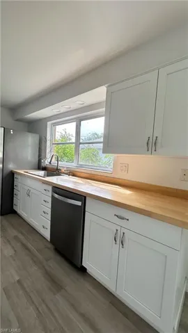 Kitchen with white cabinets, stainless steel appliances, wood-type flooring, and sink
