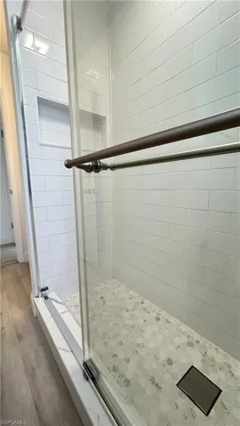 Guest Bathroom view featuring hardwood / wood-style flooring and a tile shower