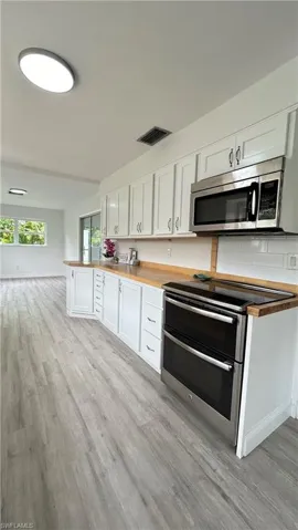 Kitchen featuring light hardwood / wood-style floors, appliances with stainless steel finishes, and white cabinets