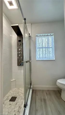 Guest Bathroom featuring walk in shower, hardwood / wood-style flooring, and toilet
