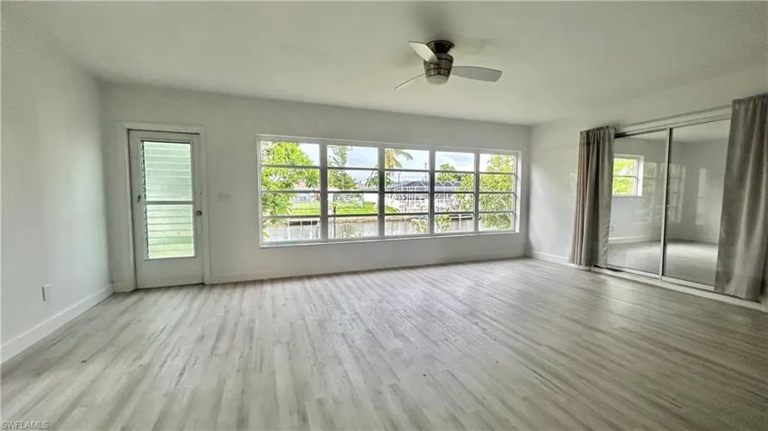 Florida room featuring ceiling fan and light wood-type flooring overlooking the canal/ under the AC.
