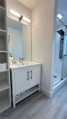 Guest Bathroom with a shower with door, hardwood / wood-style floors, and vanity