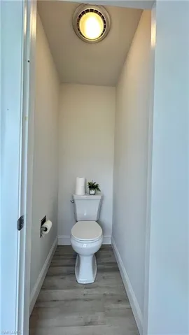 Bathroom featuring hardwood /wood-style floors and separate toilet area or powder room next to the laundry area.