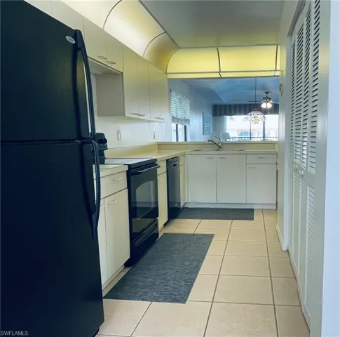 Kitchen featuring black appliances, light tile patterned floors, light countertops, ceiling fan, and white cabinetry