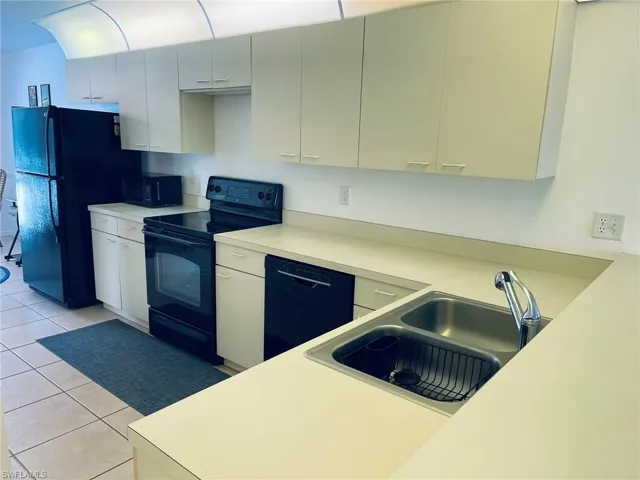 Kitchen with black appliances, light countertops, and light tile patterned floors