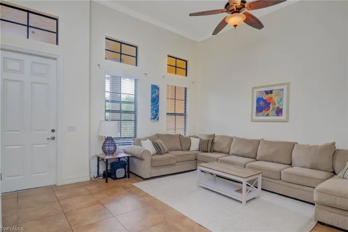 Living room with ceiling fan, light tile patterned floors, and ornamental molding