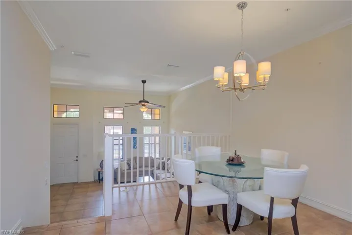 Tiled dining room featuring ceiling fan with notable chandelier and ornamental molding