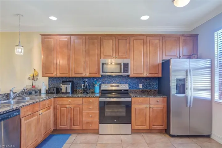 Kitchen featuring crown molding, sink, light tile patterned floors, and stainless steel appliances