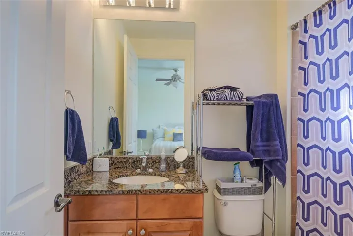 Bathroom with a shower with shower curtain, vanity, toilet, and ceiling fan