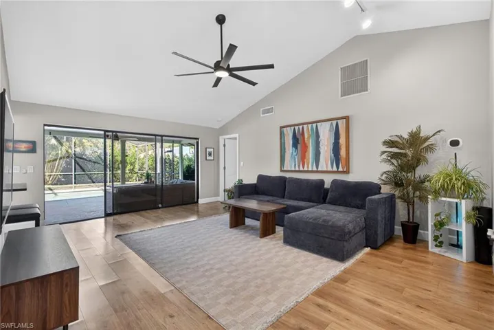 Living area featuring a ceiling fan, light wood-type flooring, vaulted ceiling, and rail lighting