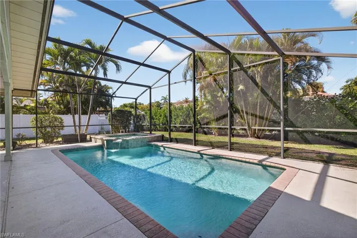 Relaxing pool / spa featuring glass enclosure, a sunroom, and a patio area