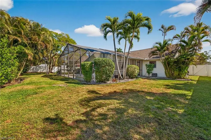 Rear view of property featuring a sunroom, a fenced backyard, glass enclosure, and a gate