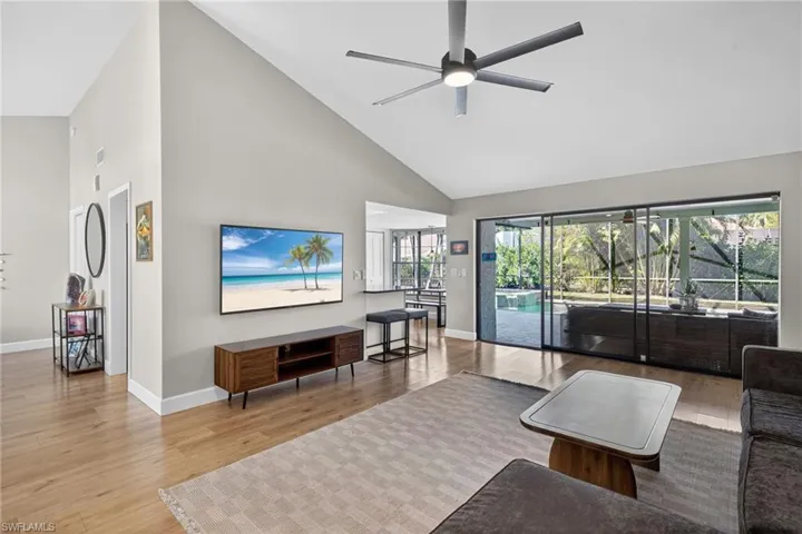 Living area featuring a ceiling fan, light wood finished floors, vaulted ceiling, and a sunroom