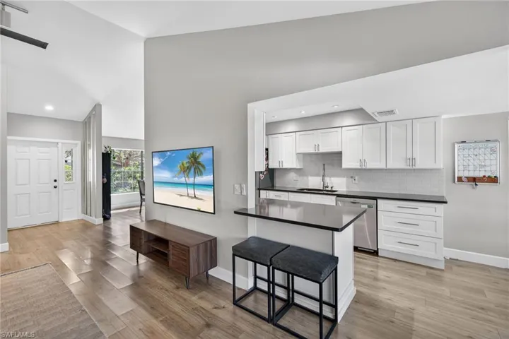 Kitchen featuring white cabinets, stainless steel dishwasher, light wood finished floors, recessed lighting, and a kitchen breakfast bar