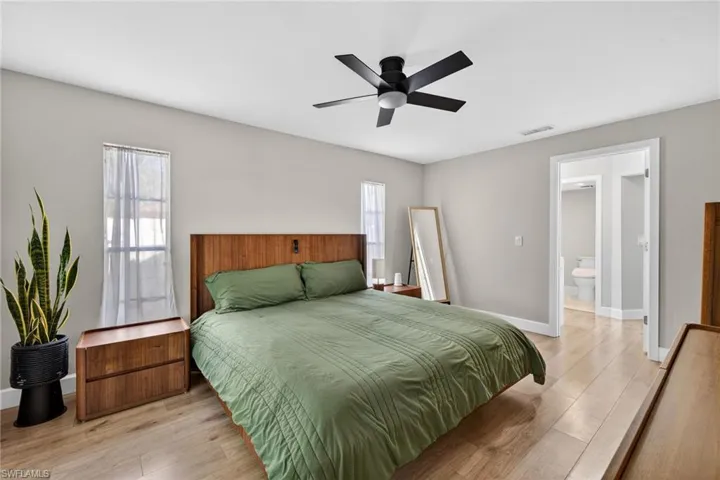 Bedroom featuring light wood finished floors, a ceiling fan, and ensuite bathroom