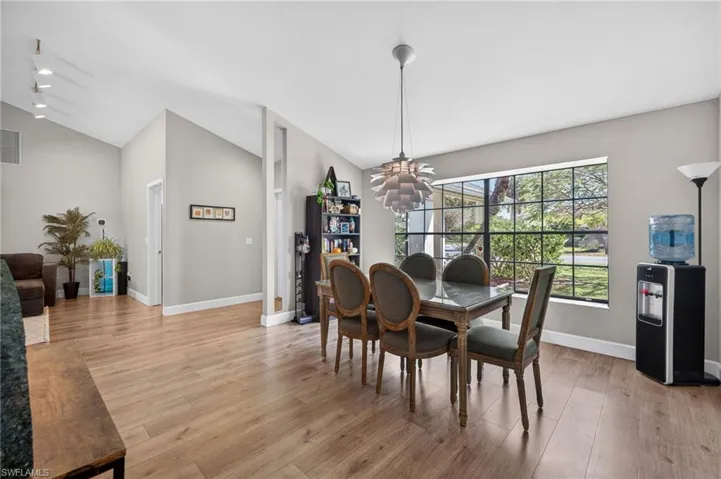Dining space featuring a chandelier, light wood-type flooring, and vaulted ceiling