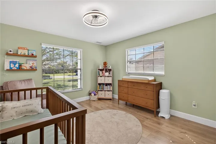 Bedroom featuring light wood finished floors and a nursery area