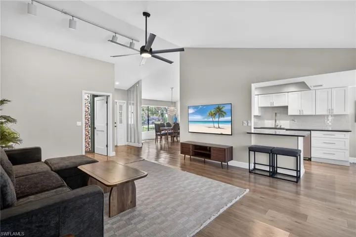 Living room featuring track lighting, lofted ceiling, light wood finished floors, and ceiling fan