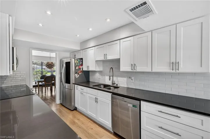 Kitchen featuring stainless steel appliances, recessed lighting, light wood-style flooring, white cabinetry, and backsplash