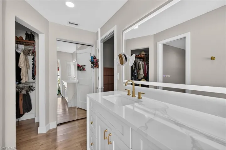 Bathroom with a spacious closet, vanity, light wood-style flooring, and recessed lighting