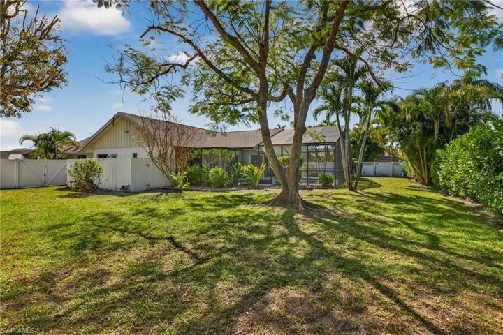 Back of house with a fenced backyard, a gate, glass enclosure, and a sunroom