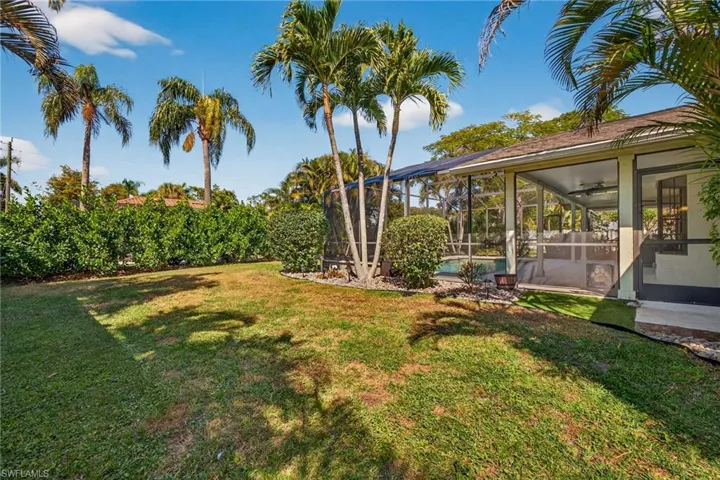 View of green lawn with a sunroom, glass enclosure, and a swimming pool