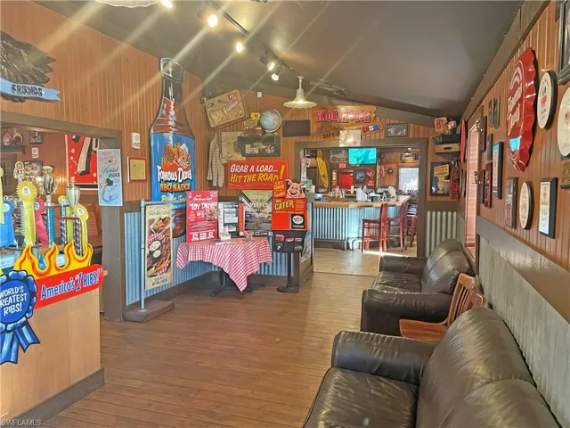 Game room featuring hardwood / wood-style flooring, lofted ceiling, rail lighting, and wooden walls