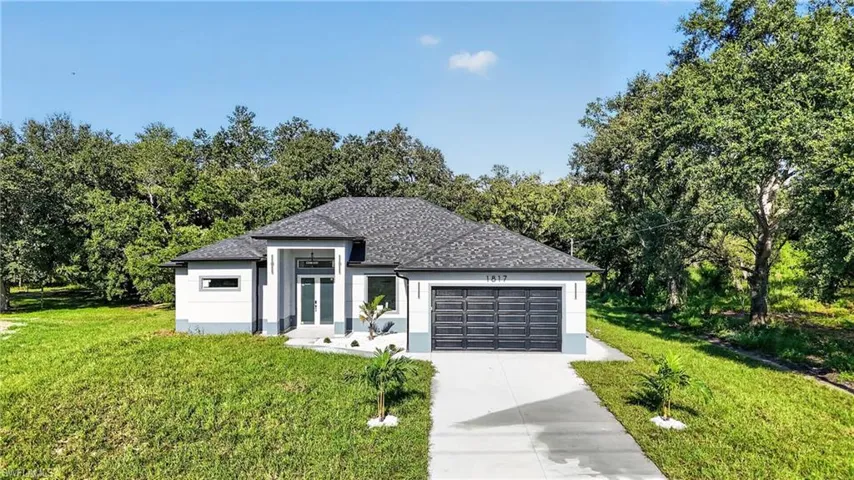 Single-story residence featuring a gray shingled roof and light-colored stucco exterior