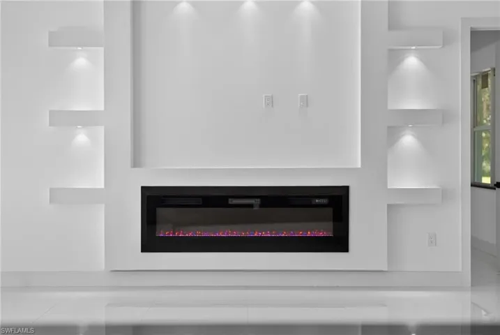 Built-in media wall with an electric fireplace, integrated shelving, and recessed lighting