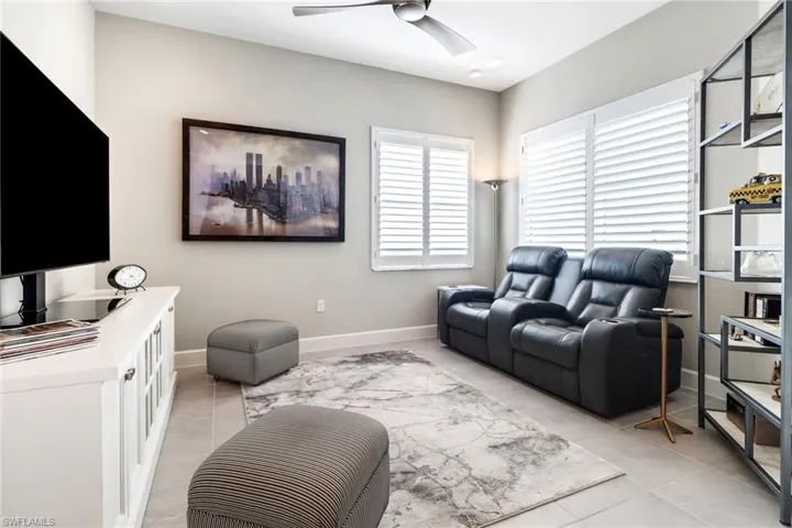 Living room with ceiling fan and light tile patterned flooring