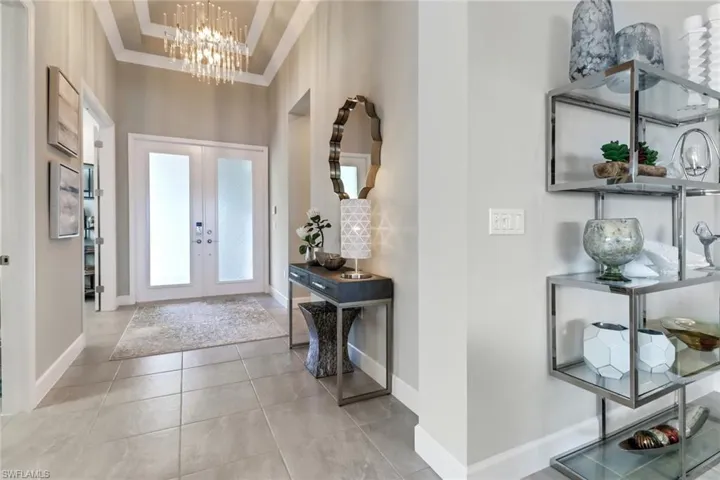 Entryway with a high ceiling, an inviting chandelier, light tile patterned floors, and french doors