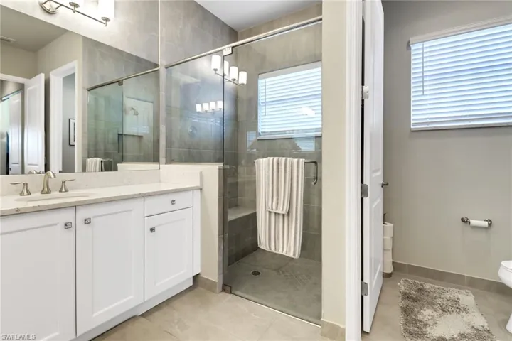 Bathroom featuring an enclosed shower, tile patterned floors, toilet, and vanity