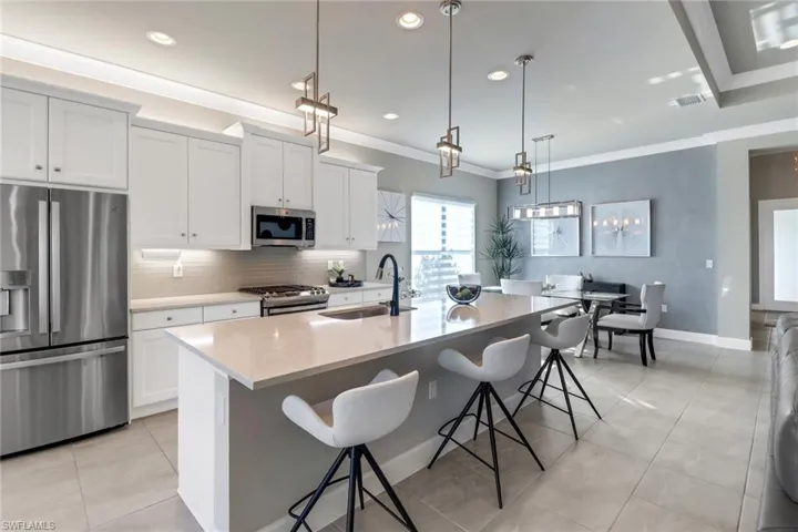 Kitchen featuring decorative light fixtures, stainless steel appliances, sink, and a center island with sink