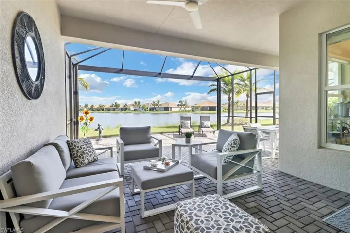 View of patio / terrace featuring glass enclosure, outdoor lounge area, ceiling fan, and a water view